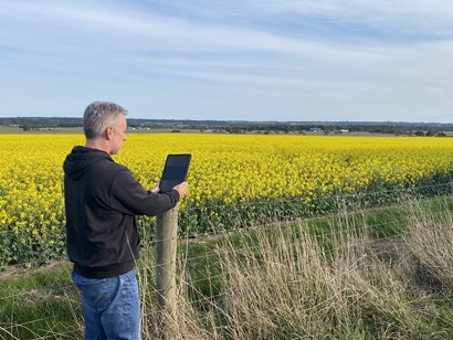 A person is looking at an iPAD in front of a field.