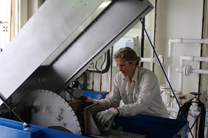 a lady uses a large dioamond saw to cut rock sample