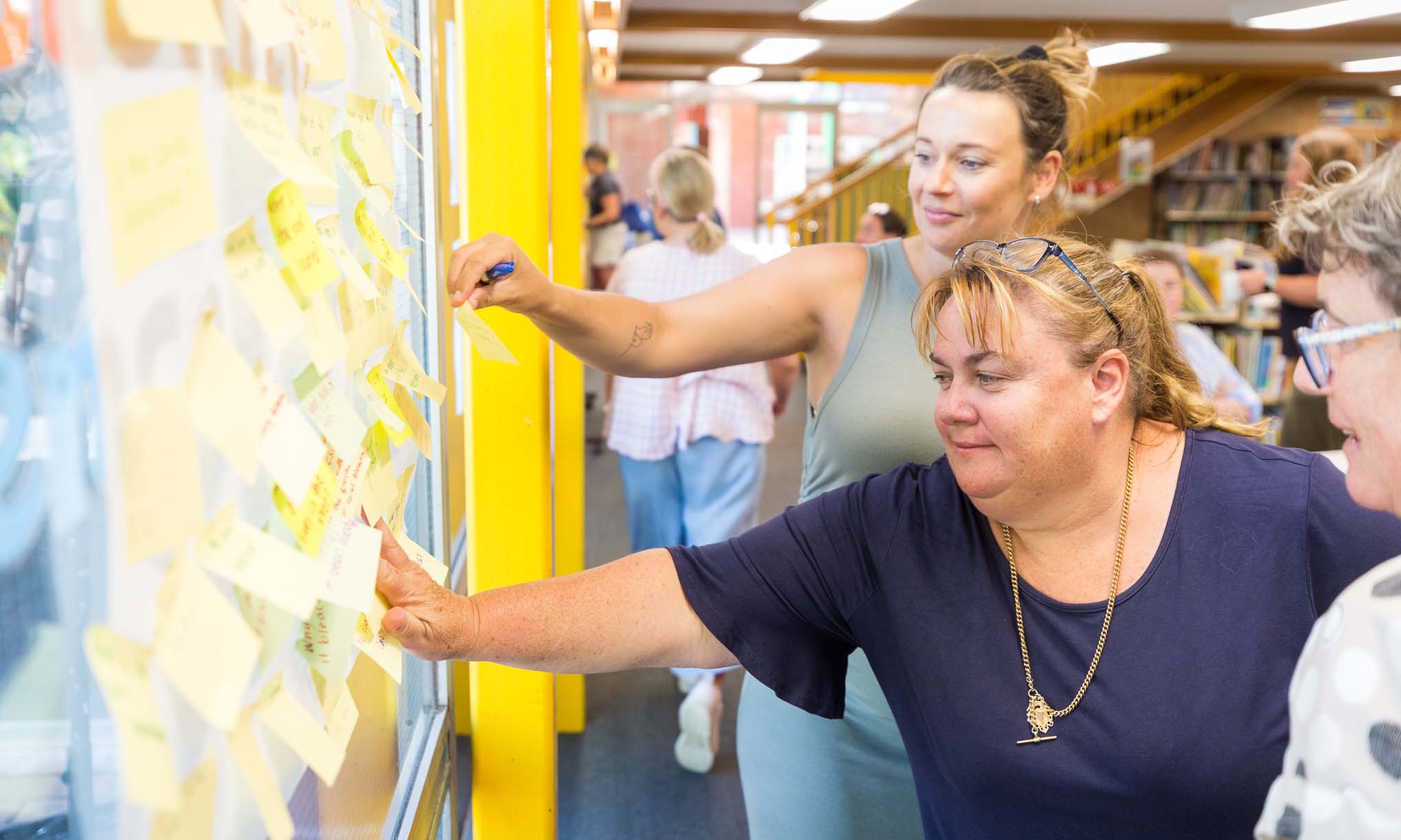 Teachers add their ideas, written on post it notes, to a wall as part of a Educator PL session
