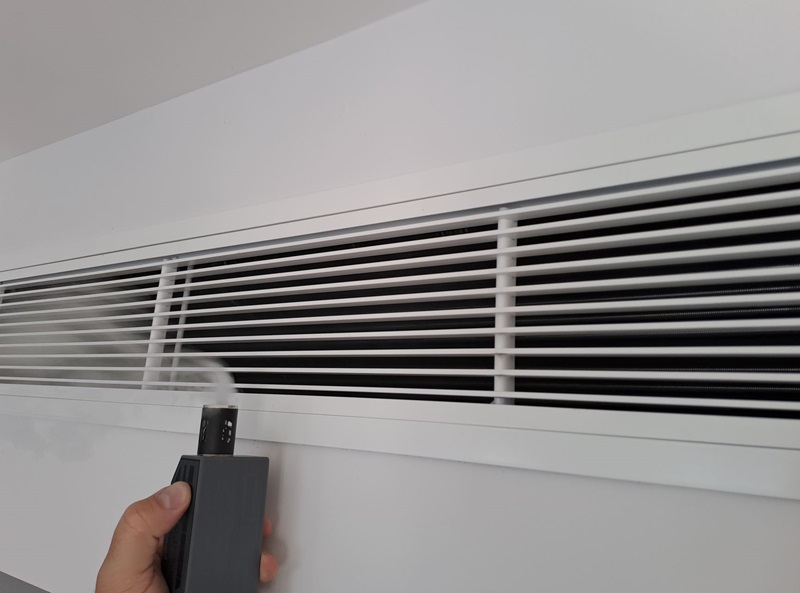 Researcher tests an air conditioning vent for air leaks