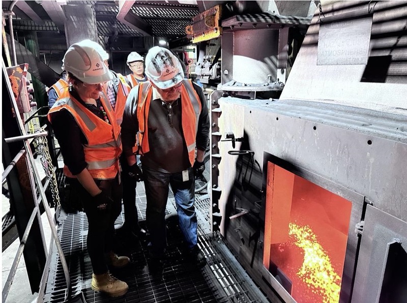 People in hard hats looking into an industrial furnace