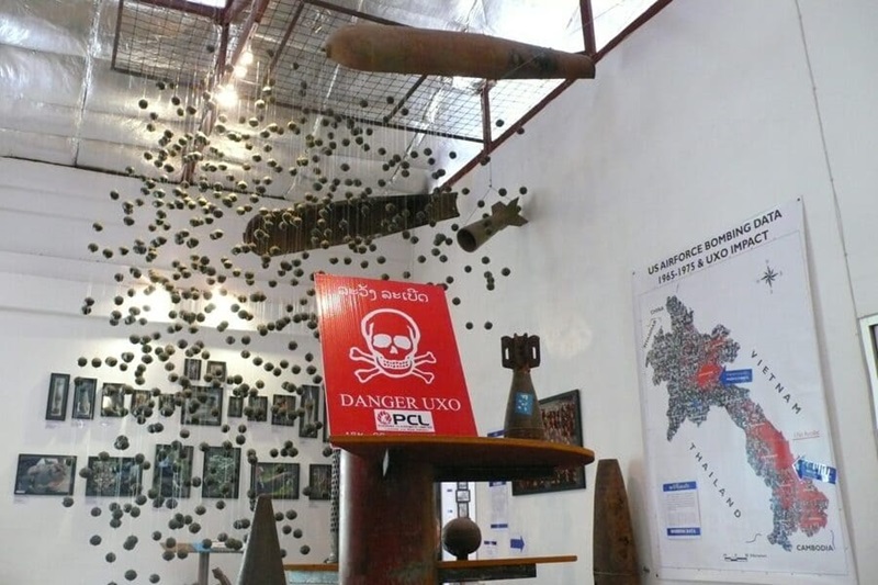 Display at Cope Visitors Centre in Laos showing a map on the wall with landmine sites, a landmine warning sign 