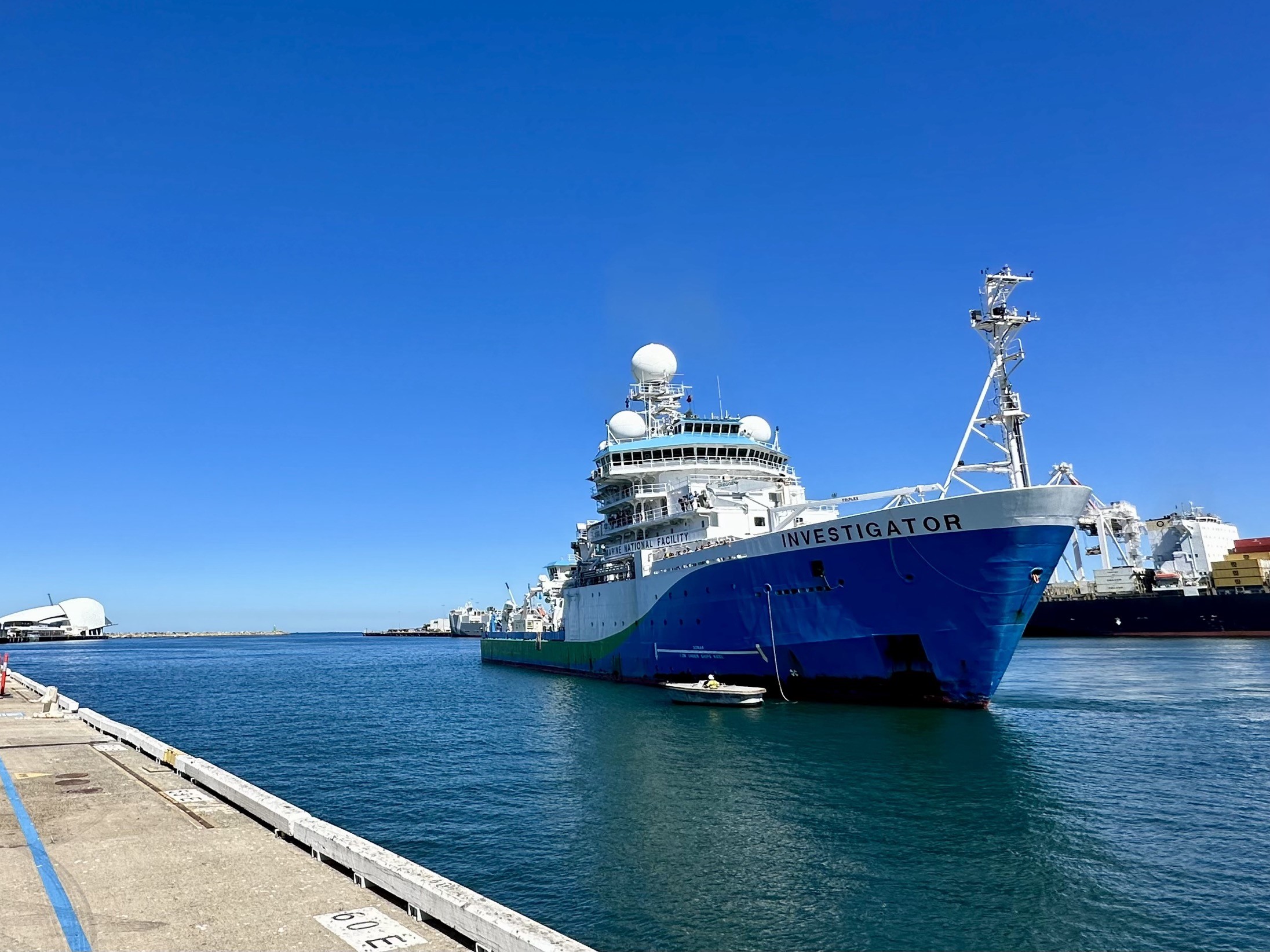 A large blue and shite ship next to a wharf.