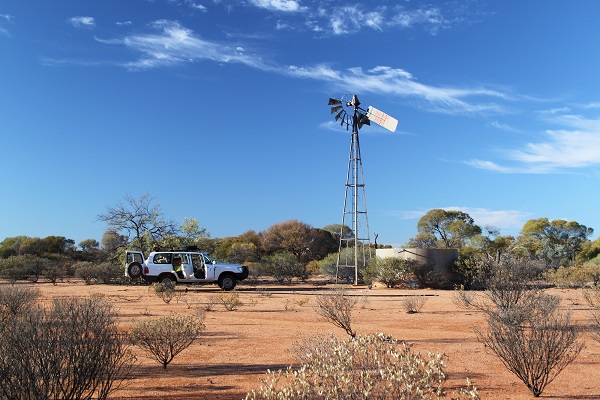 Truck next to windmill and water in arid landscape tank 
