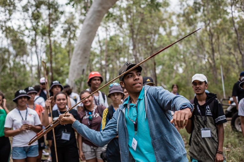 Student preparing to throw a spear with group of student onlookers 