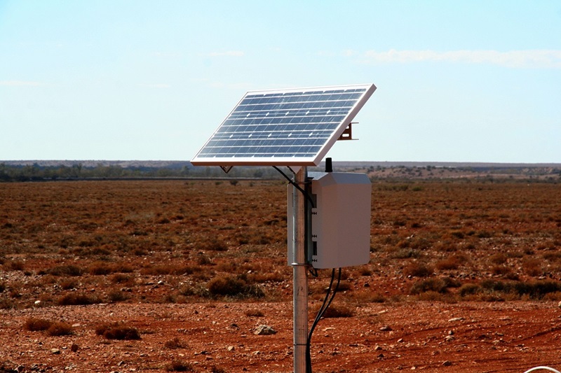 solar panel on top of a post with a box of electronics attached 