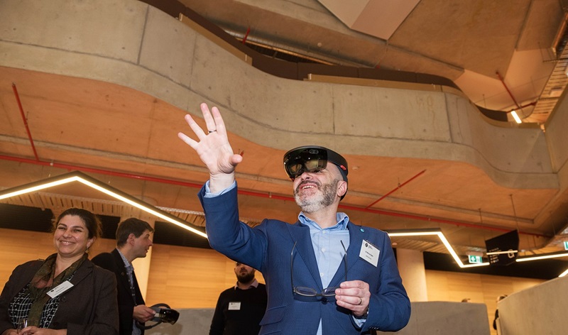 Bearded man wearing transparent google headset shown reaching into empty space