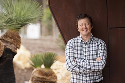 Man standing in front of rusted wall in a garden