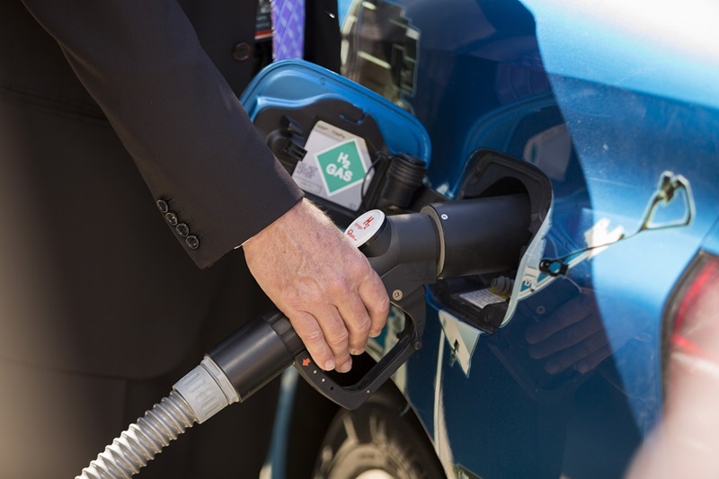 Closed up of a had on a hydrogen fuel bowers trigger nozzle filling the fuel tank on a car