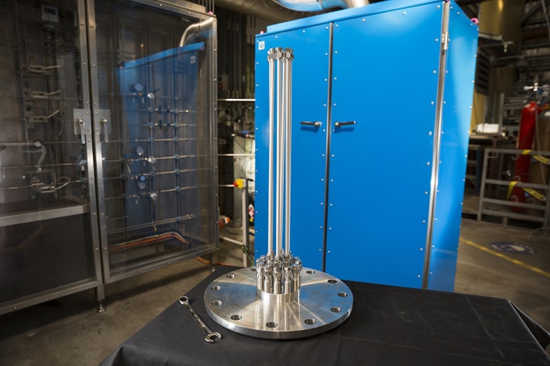 Metal rods arising from a circular metal base with a blue painted metal locker in the background