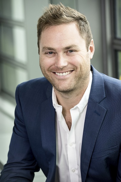 Head and should portrait of man wearing blue suit jacket and open collar white shirt