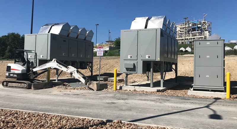 Three metal units, a bobcat diggers and mining plant in the background