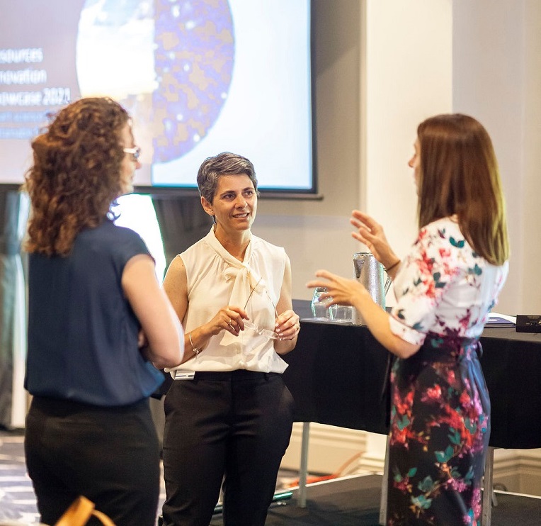 three women gathered discussing geology presentation