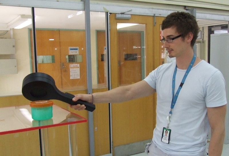 Man holding paddle shaped probe over cylindrical container