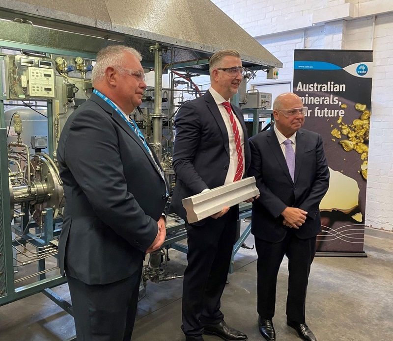 Three men, one holding a magnesium alloy ingot