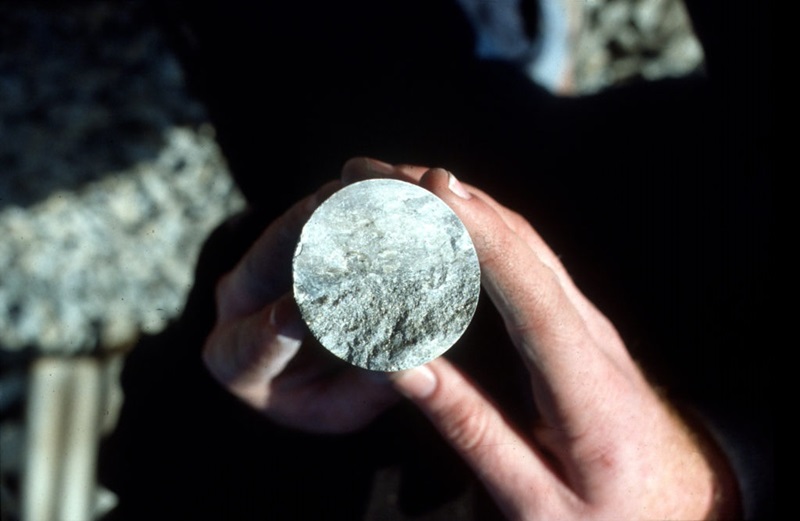 Close-up of hands holding a cross section of drill core