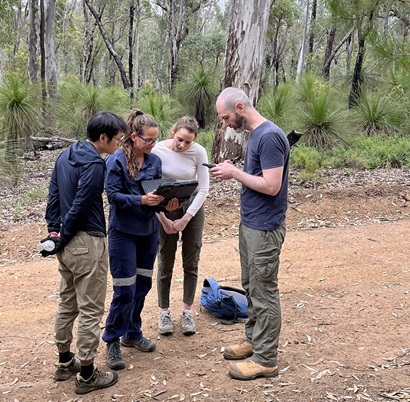 Four people in the field looking at device screen