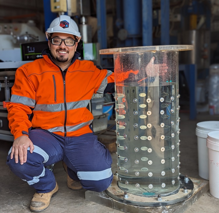 Man in hire visibility clothing squatting next to clear tank