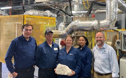 Dr Chris Griffith with four team members in a lab, one person holding a large rock sample