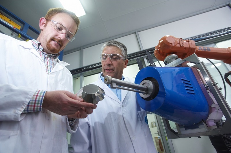 One man holding metal object and seonc man holding cold spray gun equipment