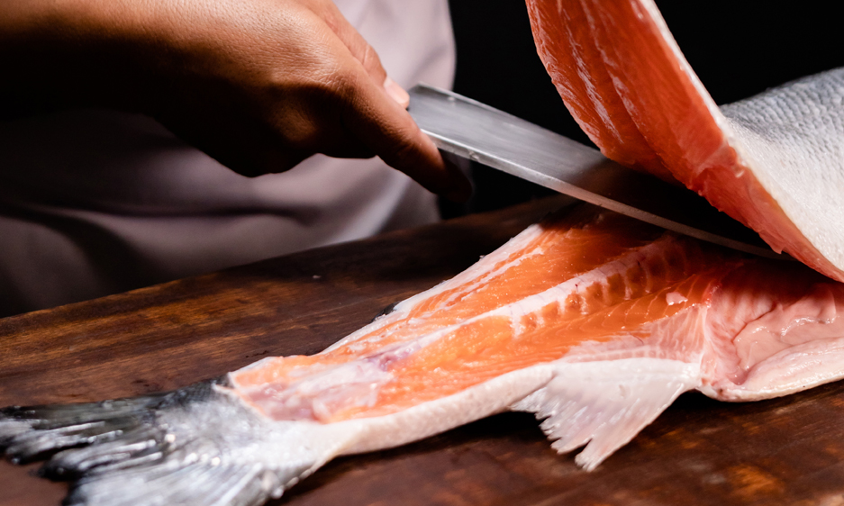 Close-up of a chef slicing into a salmon