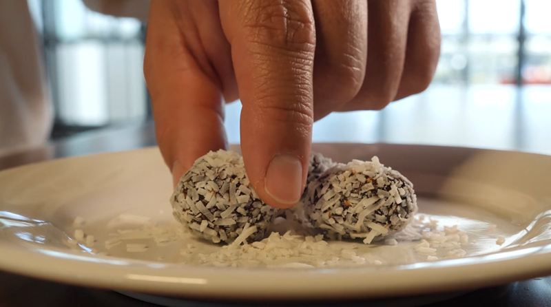 Hand picking up a protein ball from a plate