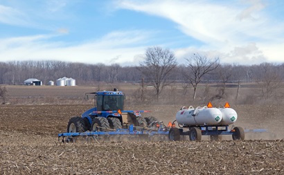 Photo of a tractor in a field pulling a trailer with two horizontal cylindrical tanks