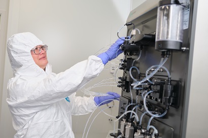 Person in protective clothing working with equipment in the National Vaccine and Therapeutics Lab.