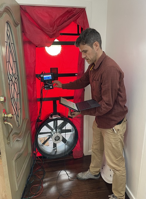 Researchers conducting a blower door test to identify leakage rate, and determine where leakages occur.  