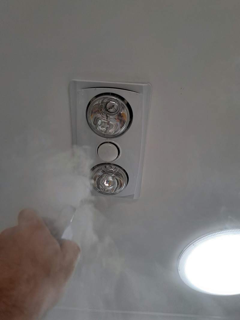 A bathroom roof exhaust fan is being sprayed with steam to show a current being blown into the house via the fan.