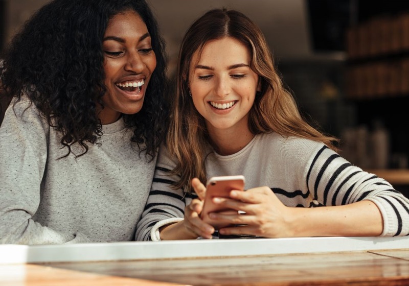 Two people looking at a mobile phone together and smiling