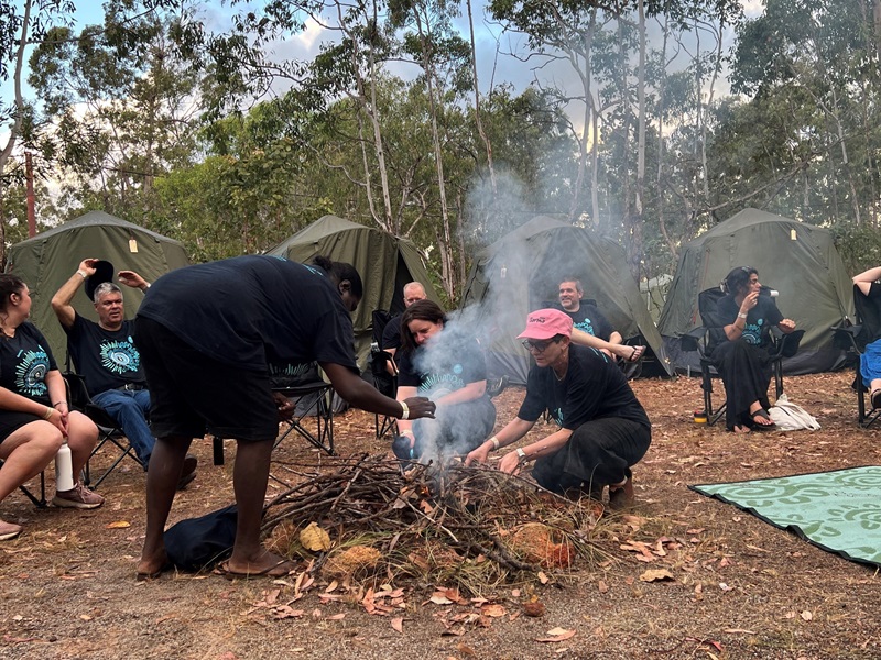 Members of the 2024 Garma CSIRO delegation, gathered around a campfire at their campsite.