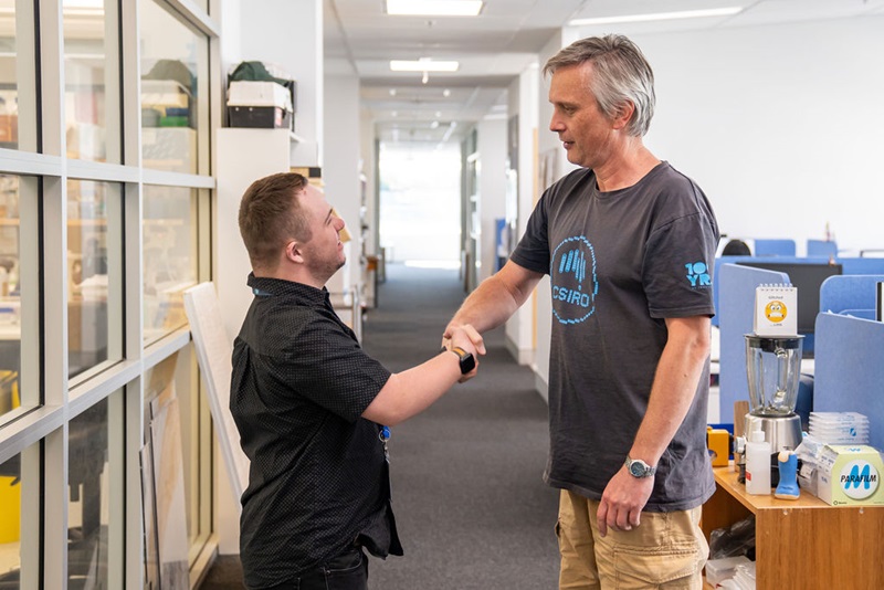 Two people shaking hands in an office.