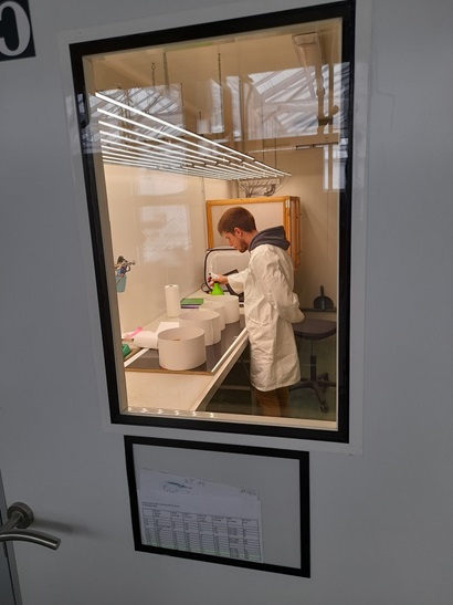 Looking through laboratory door at scientist Cedric Kosciolek as he uses circular snail arenas to run snail colour preference tests in the laboratory