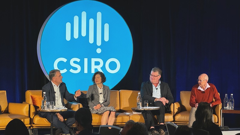 Three men and a woman sit on a stage with a large CSIRO logo behind them.