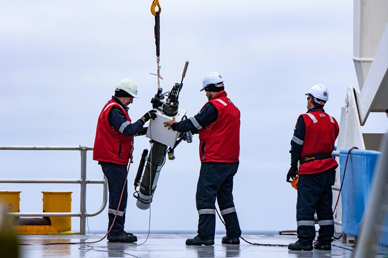 Three researchers deploy a robotic float off a CSIRO research vessel.