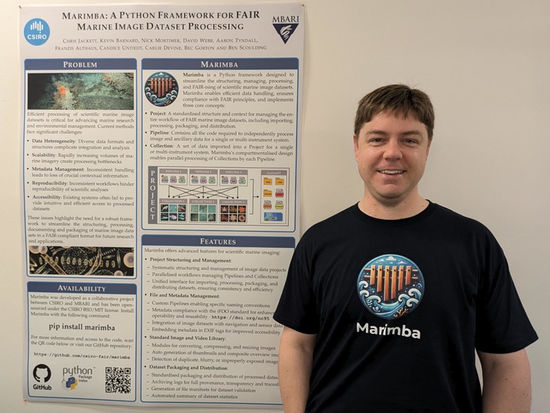 A man stands in front of a science poster attached to a wall.