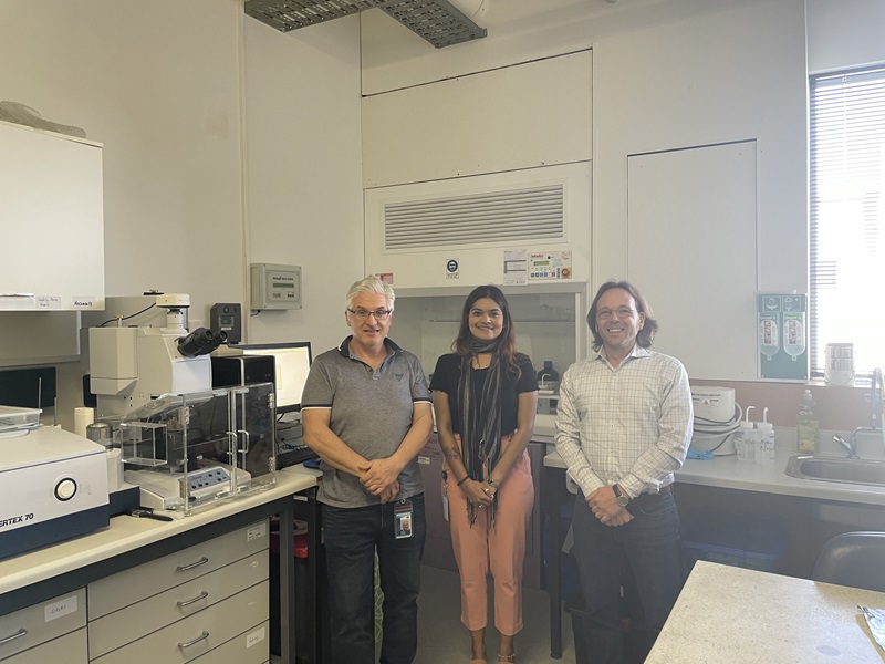 Three people standing in a lab smile for the camera. 