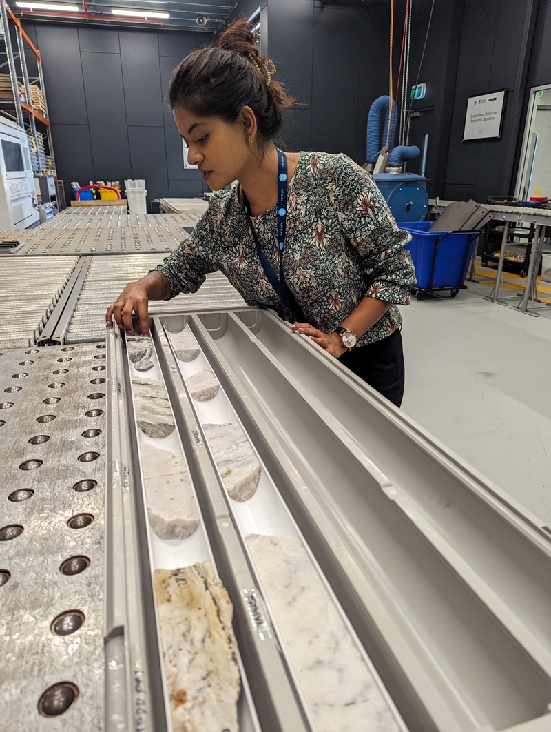 Dr Naina leaning over and inspecting a series of drill core samples