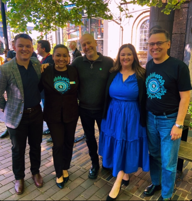 A group of people pose, smiling for the camera. 