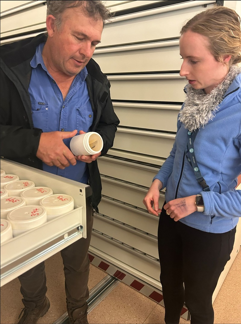 Two people examine a plastic container. 