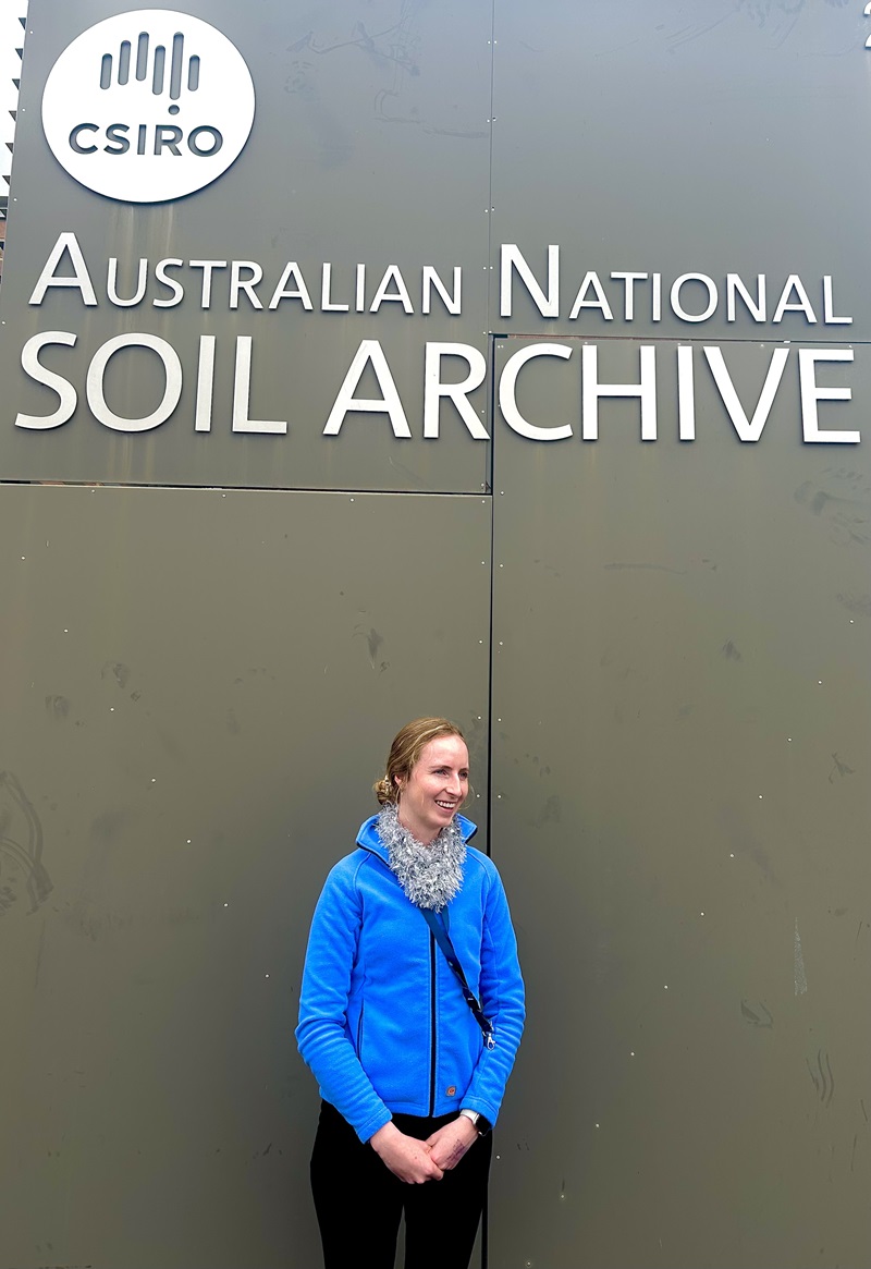 Georgia posing in front of a sign that says Australian National Soil Archive below the CSIRO logo. 