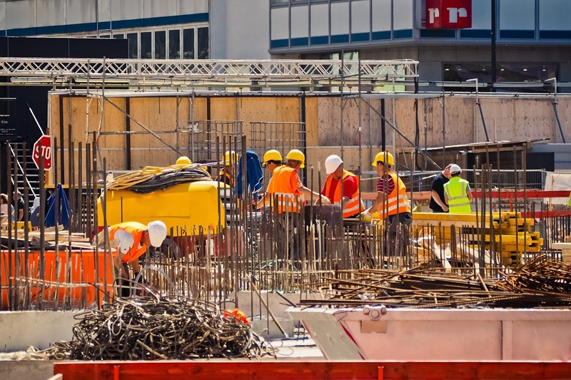 Construction workers wearing hard hats and safety vests are working on a building site