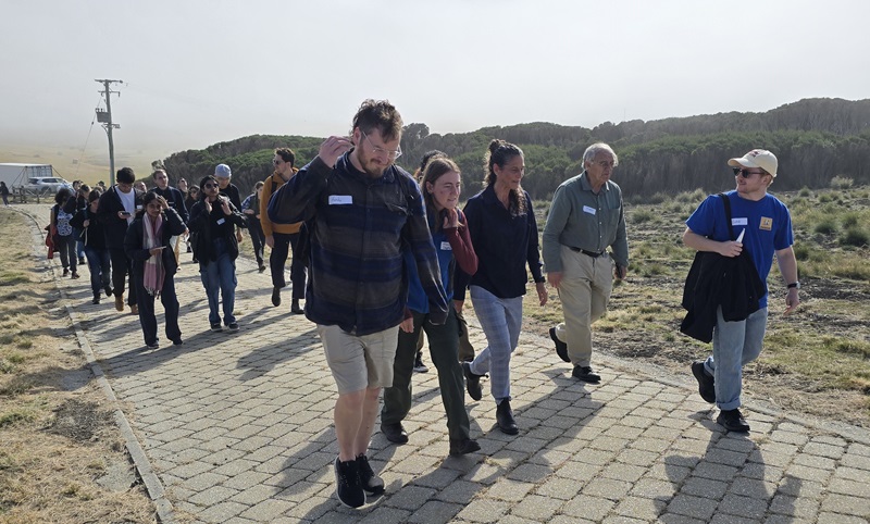 A large group of people wearing hand-written nametags walk up a paved footpath.