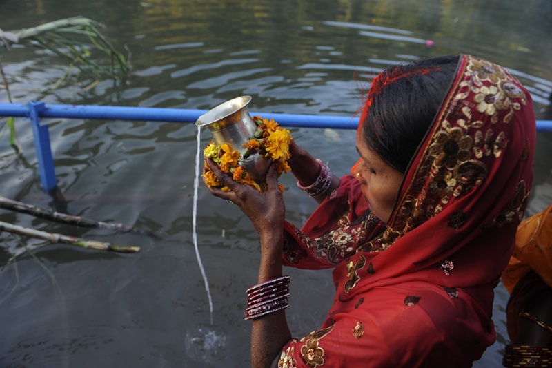 A women pours water from a jug into the river