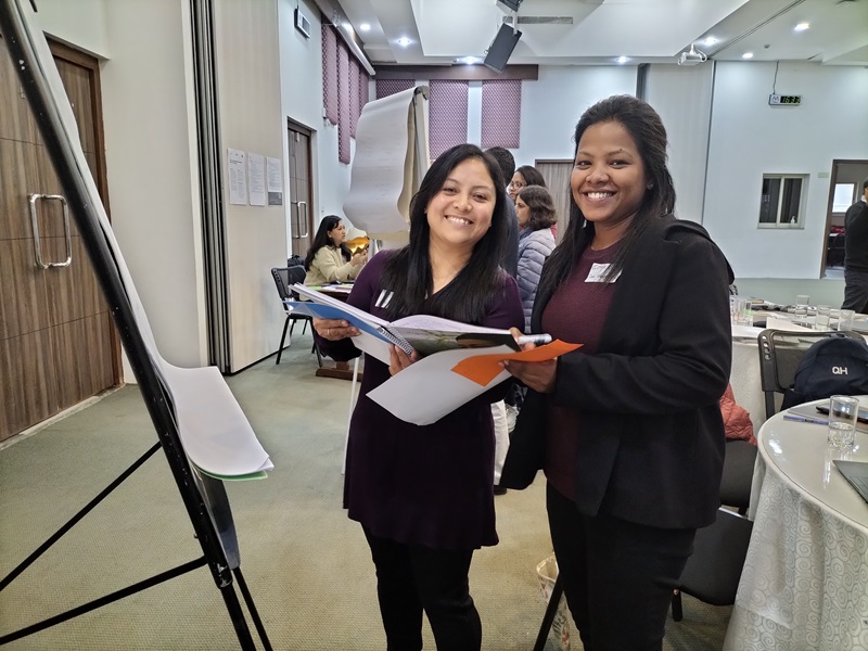 Two women stand beside a flip chart in discussion