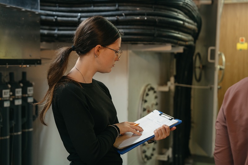 A person standing in a scientific laboratory holding a clipboard.