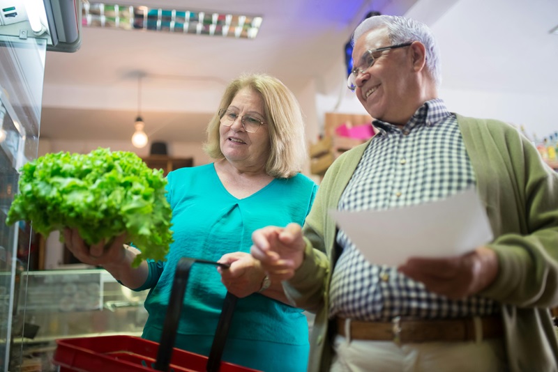 An older woman and man examine a head of lettuce.