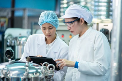 Asian woman teaching a coworker while in a food and beverage environment